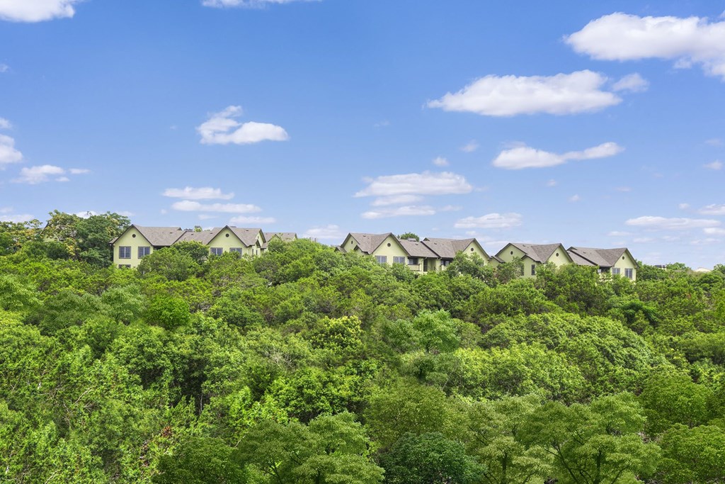 a row of apartments sitting on top of a lush green forest